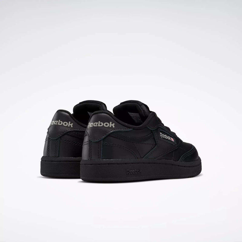 A pair of Kids' Club C Shoes by Reebok, featuring a black leather upper with dark green accents and visible Reebok logos on the heel and side, shown from the back and side on a plain white background.