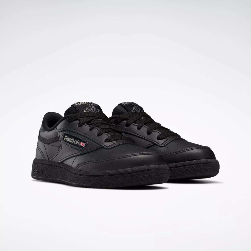 A pair of black Reebok Kids' Club C Shoes for little kids with laces, leather upper, Reebok branding, and Union Jack flag on the side are displayed on a light background.