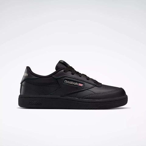 The Kids' Club C Shoes - Little Kids by Reebok are black low-top sneakers with a leather upper, Reebok logo and British flag on the side, black laces, and a black rubber sole, shown against a plain light gray background.