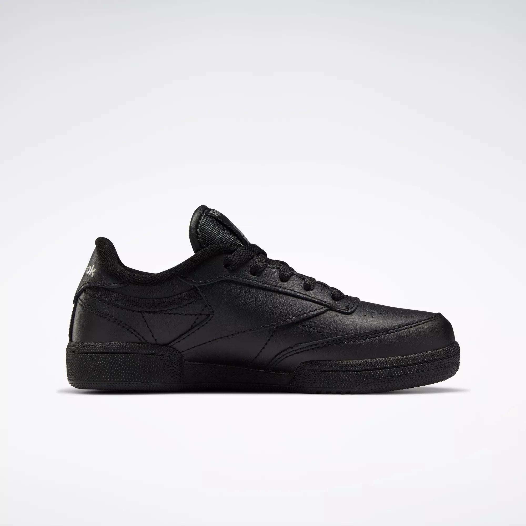 The Reebok Kids' Club C Shoes - Little Kids feature a black leather upper, black laces, subtle stitching details, and a simple low-top design, displayed on a plain white background.