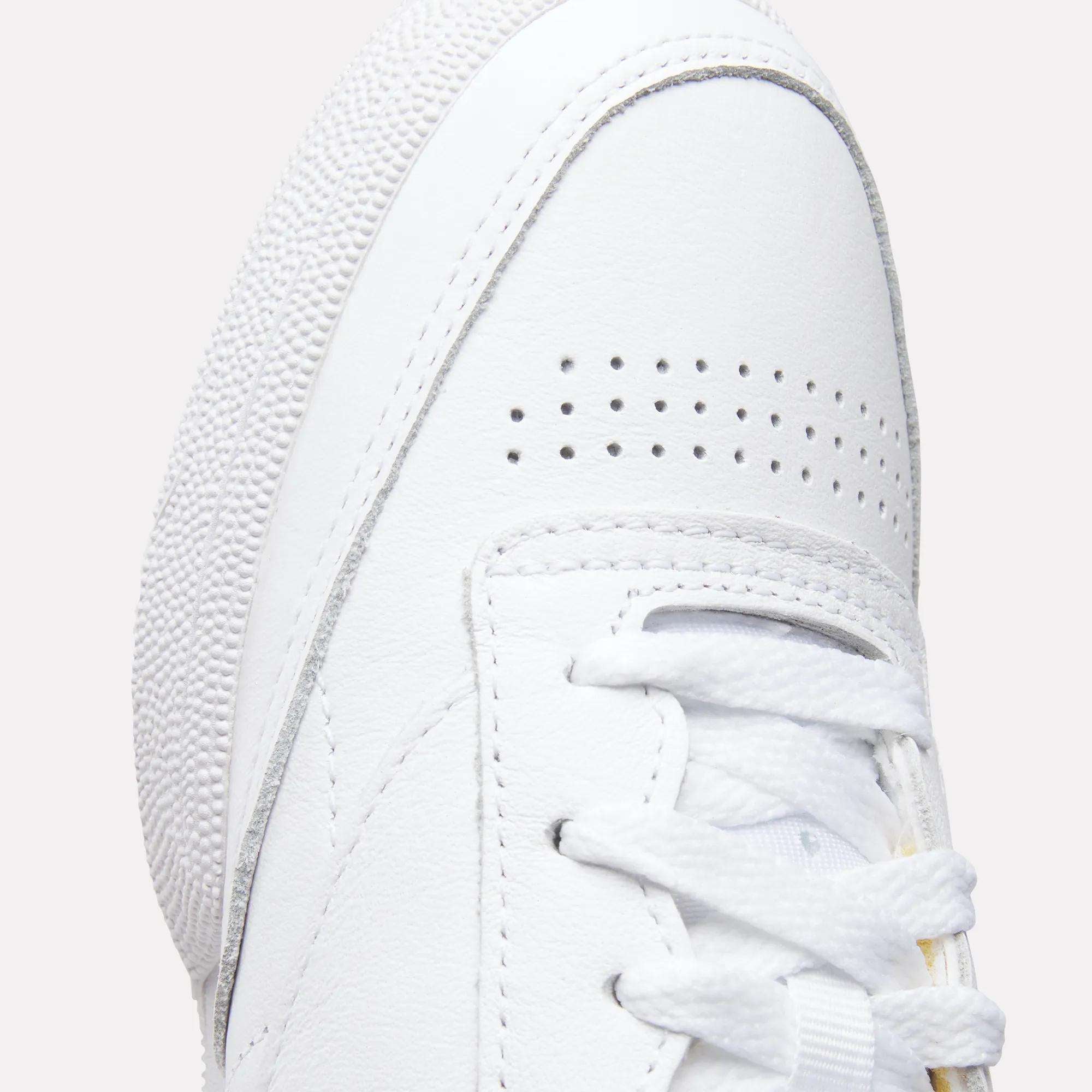 Close-up of the toe and laces on the Reebok Women's Club C 85 Shoes, highlighting perforated details on the toe box, a textured rubber sole, and white stitching on smooth leather.
