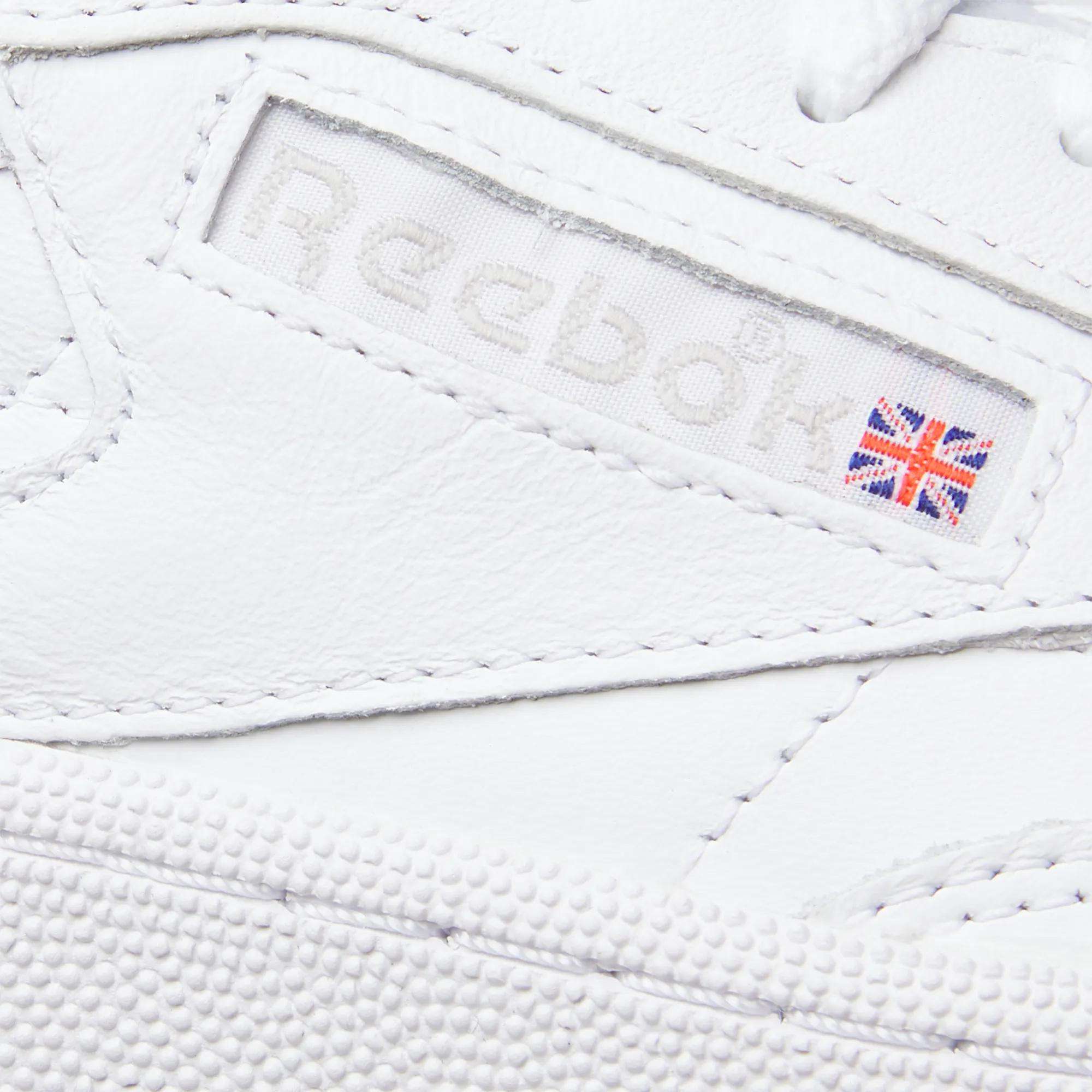 Close-up of Reebok’s Women’s Club C 85 Shoes in white, featuring a stitched Reebok logo and Union Jack on the side. The textured leather material offers classic style—making these sneakers an iconic pick for women.