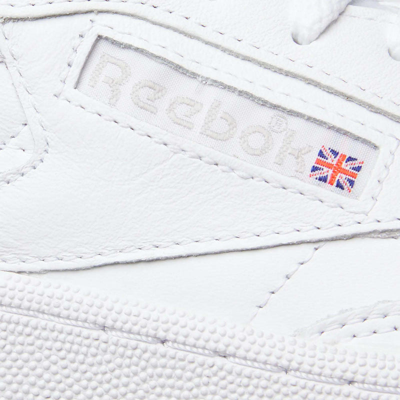 Close-up of Reebok’s Women’s Club C 85 Shoes in white, featuring a stitched Reebok logo and Union Jack on the side. The textured leather material offers classic style—making these sneakers an iconic pick for women.