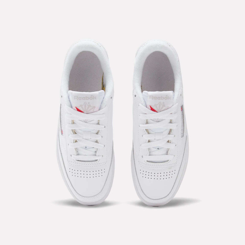 A top view of the Reebok Women's Club C 85 Shoes shows white sneakers with white laces, perforated toe boxes, and red-accented Reebok logos on the tongue and side.