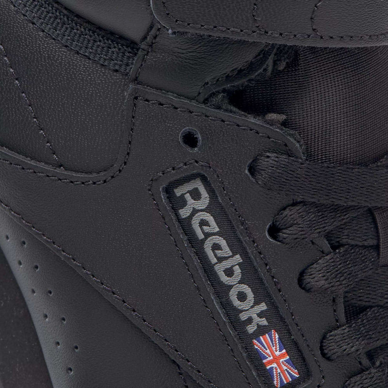 Close-up of the Reebok Women's Freestyle Hi Shoes, a black high-top sneaker with black laces, detailed stitching, and the Reebok logo plus Union Jack flag on the side—ideal for women’s fitness enthusiasts.