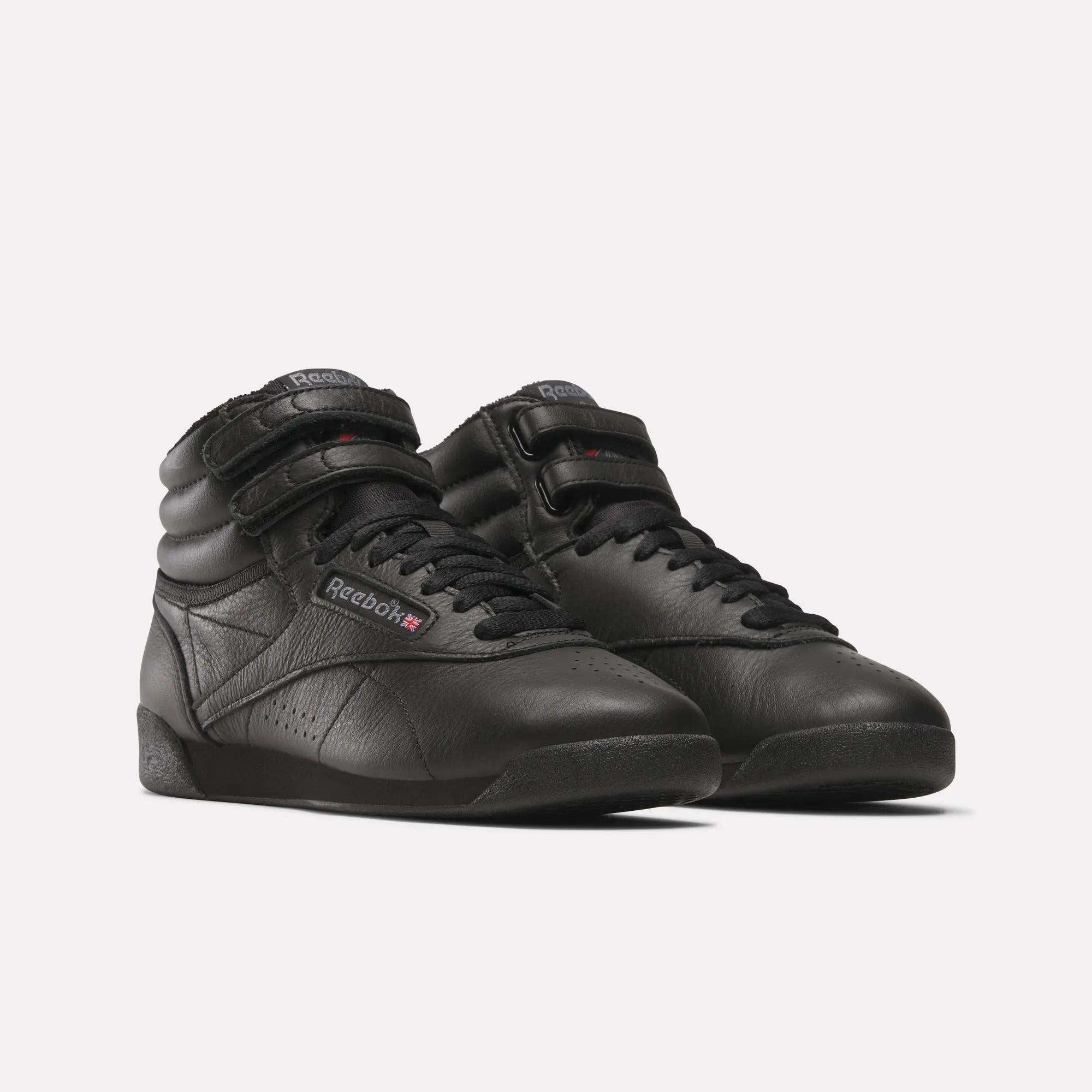 The Women's Freestyle Hi Shoes by Reebok feature a black high-top design with Velcro straps and leather uppers, ideal for women's fitness, shown against a plain white background.