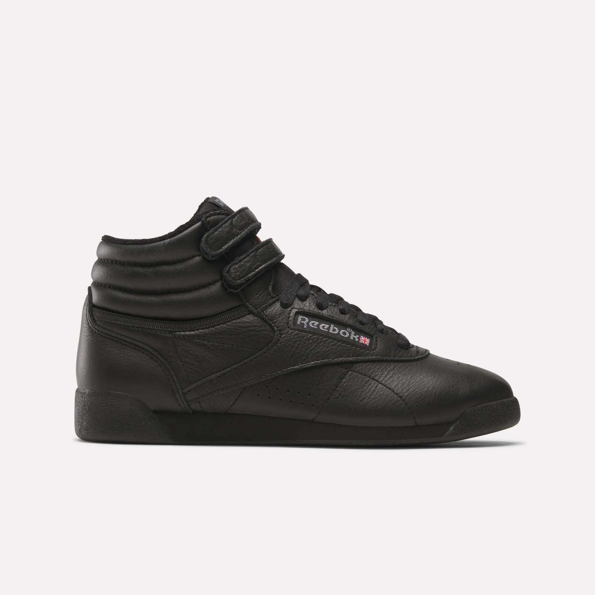 The Reebok Women's Freestyle Hi Shoes are black high-top sneakers with a leather upper, dual ankle Velcro straps, black laces, and a side Reebok logo—ideal for women's fitness. Shown against a plain white background.