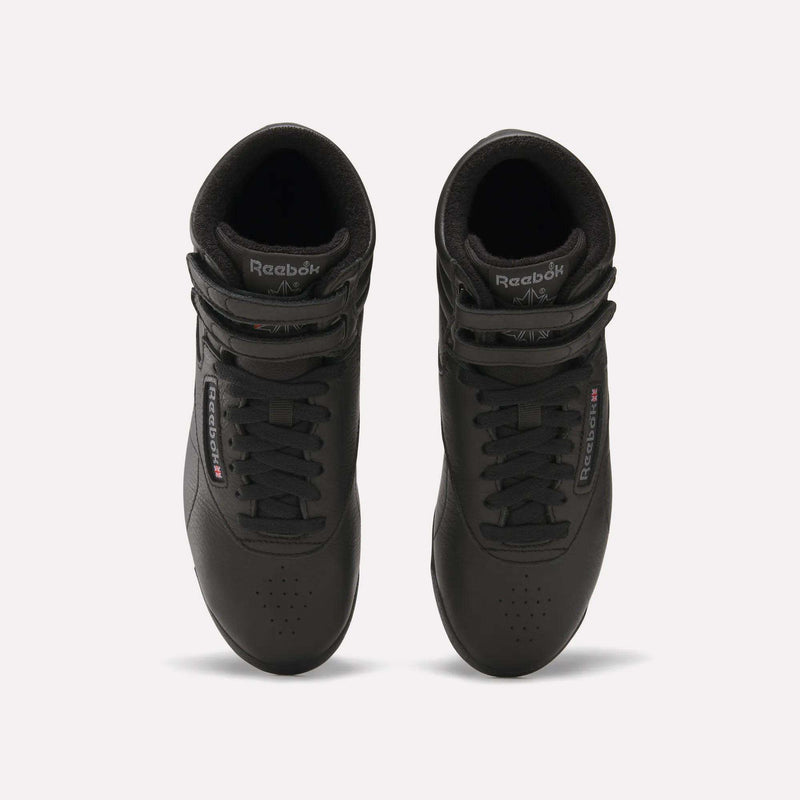 Top view of a pair of Women's Freestyle Hi Shoes by Reebok in black, featuring Velcro straps, laces, and the Reebok logo on tongue and side. Stylish women's fitness sneakers set side by side on a plain white background.