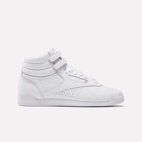 The Reebok Freestyle Hi Women's Shoes are white high-top trainers with two velcro ankle straps, white laces, and a textured sole, shown on a plain white background.