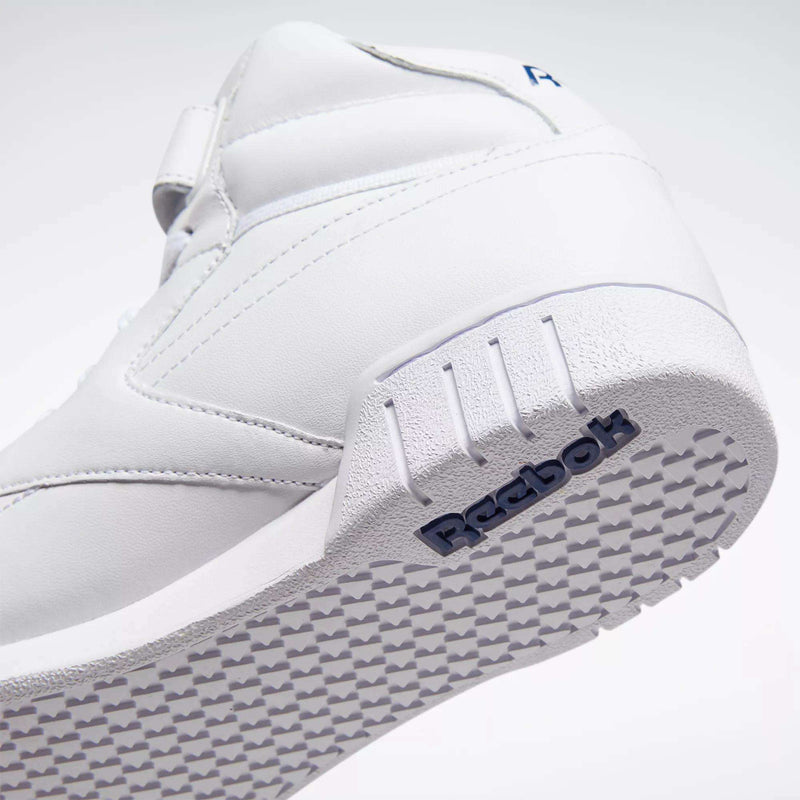 Close-up side view of the Reebok Men's EX-O-FIT Hi Shoes in white leather, featuring a textured sole, subtle stitching, and a dark blue embossed Reebok logo near the heel for a vintage look.