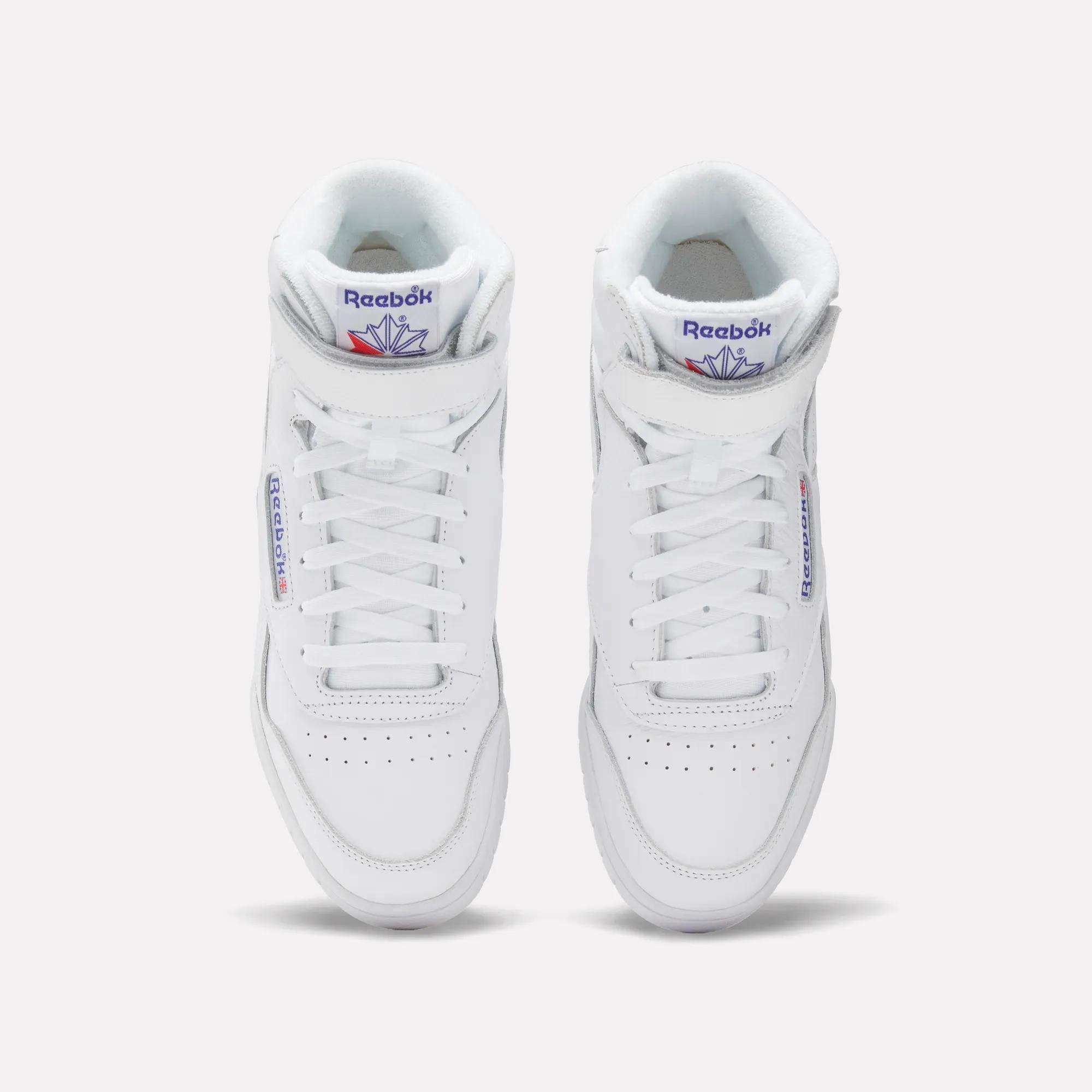 A pair of Men's EX-O-FIT Hi Shoes by Reebok, in white leather with blue and red logo details on the tongue and side, shown from above on a light background, radiating classic old-school style.