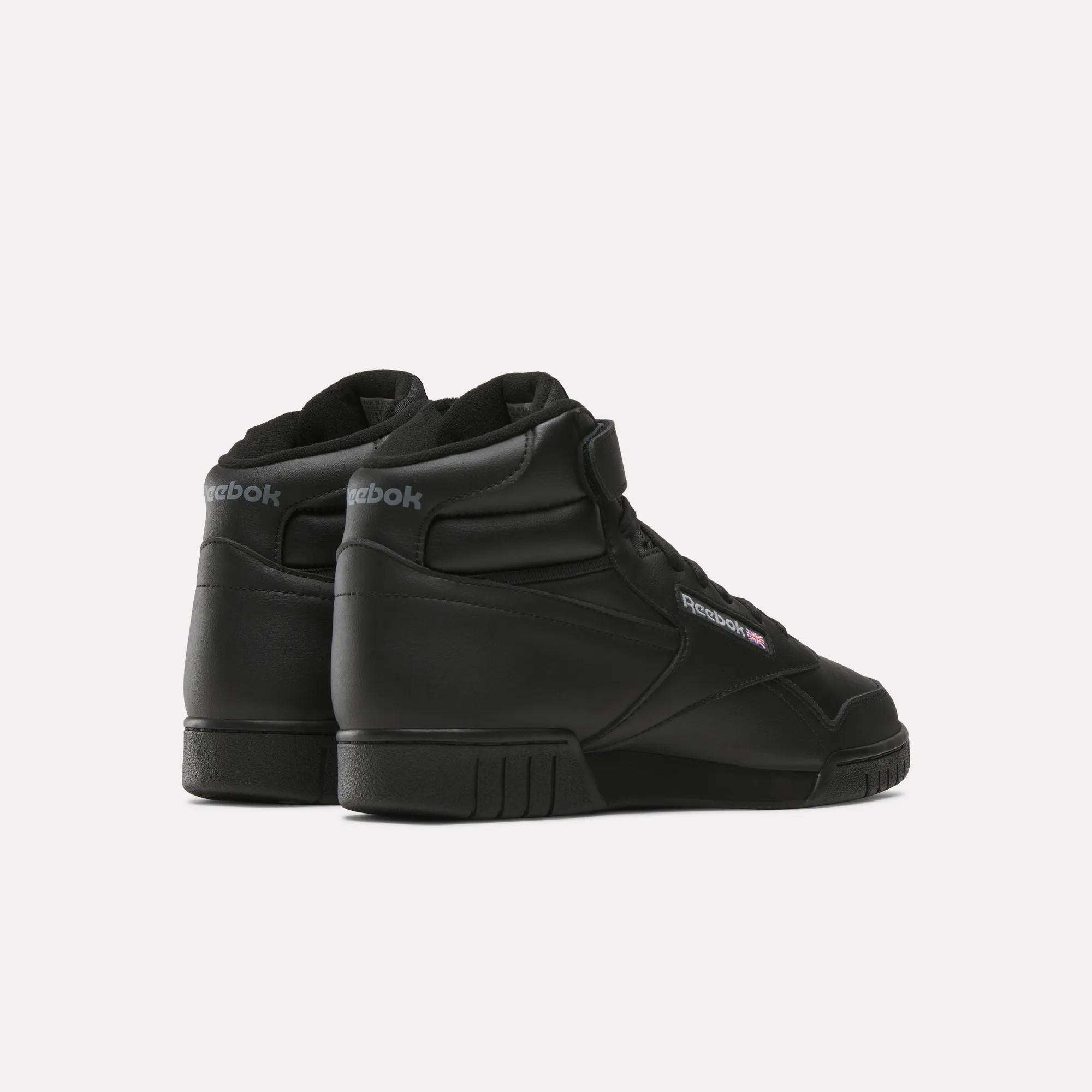The Reebok Men's EX-O-FIT Hi Shoes are displayed at an angle on a plain white background, showing the back and outer sides of both black high-cut sneakers with a classic leather design.