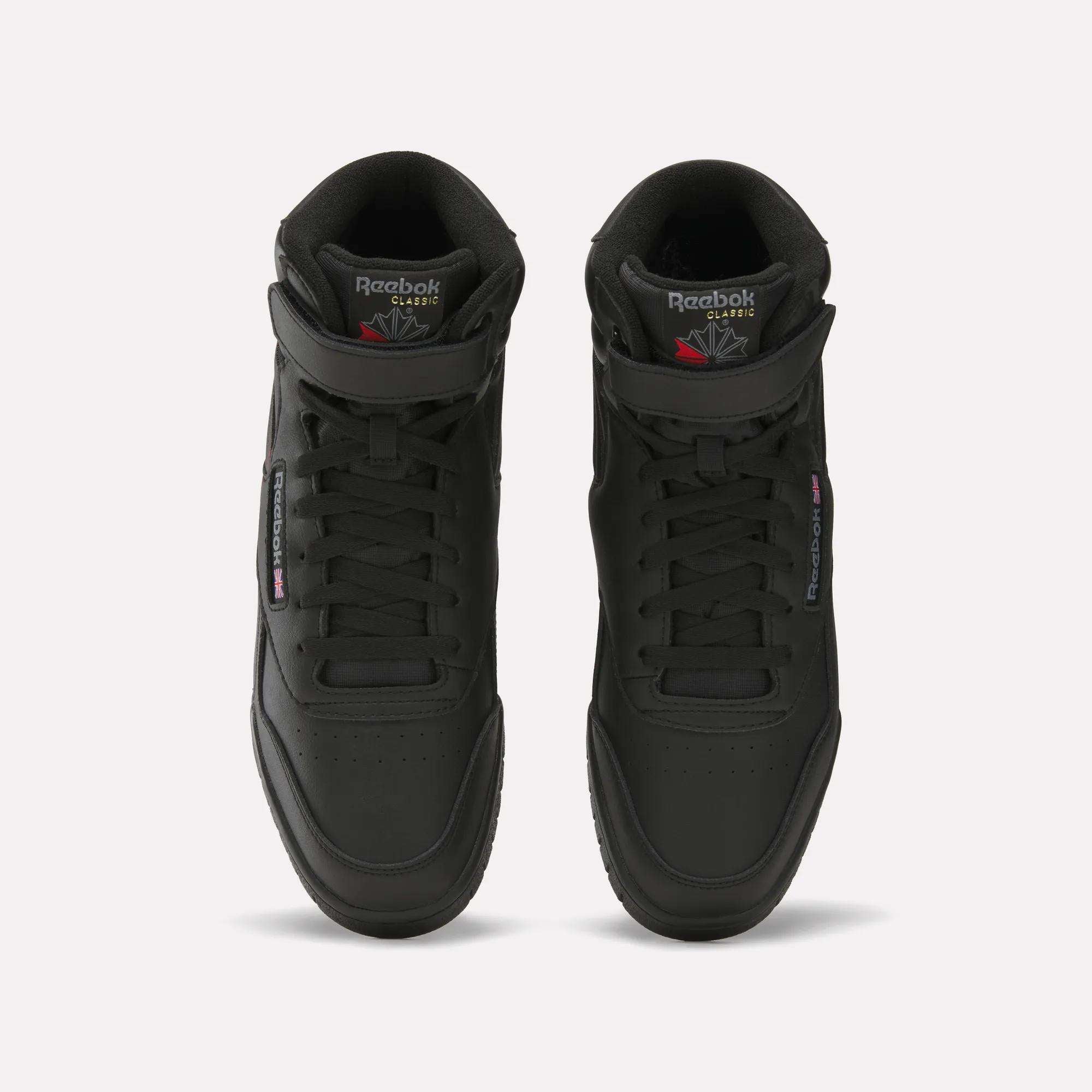 A pair of black Reebok Men's EX-O-FIT Hi shoes with an old-school design, viewed from above, featuring perforated toes, laces, and Reebok branding on the tongues and sides.