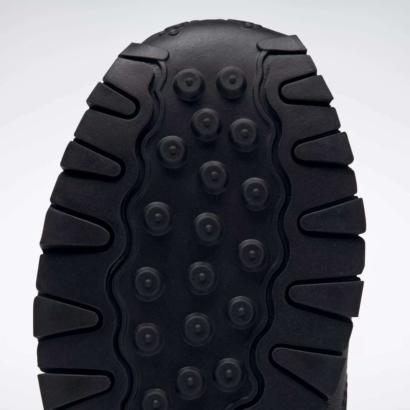 Close-up of the black sole on Reebok Kids' Classic Leather Shoes - Preschool, showing thick, rugged treads and circular indents for traction and durability, plus lightweight cushioning for all-day comfort.