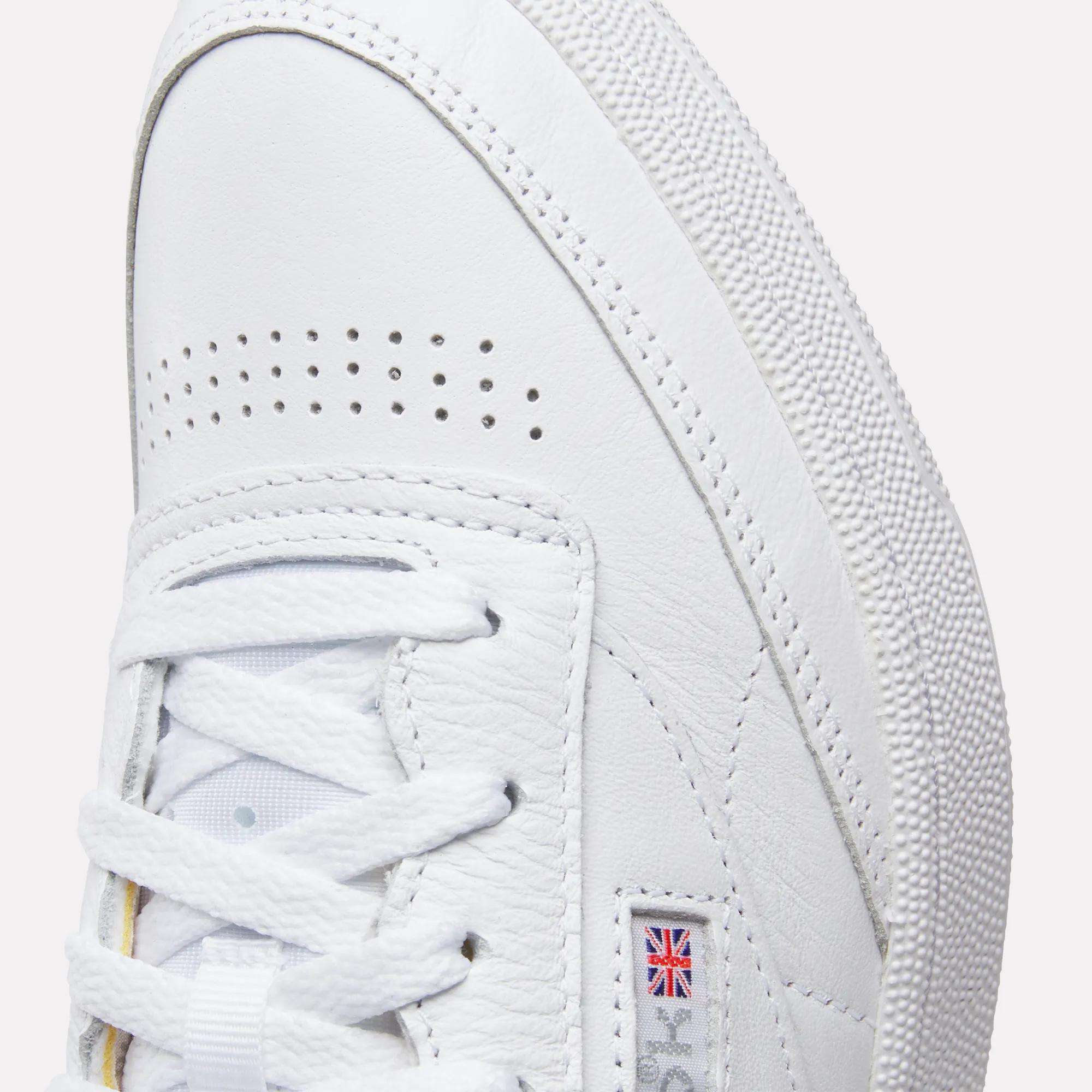 Close-up of the toe and side of Reebok Club C 85 Shoes, featuring textured white leather, white laces, small perforations, and a mini UK flag logo patch on the side.