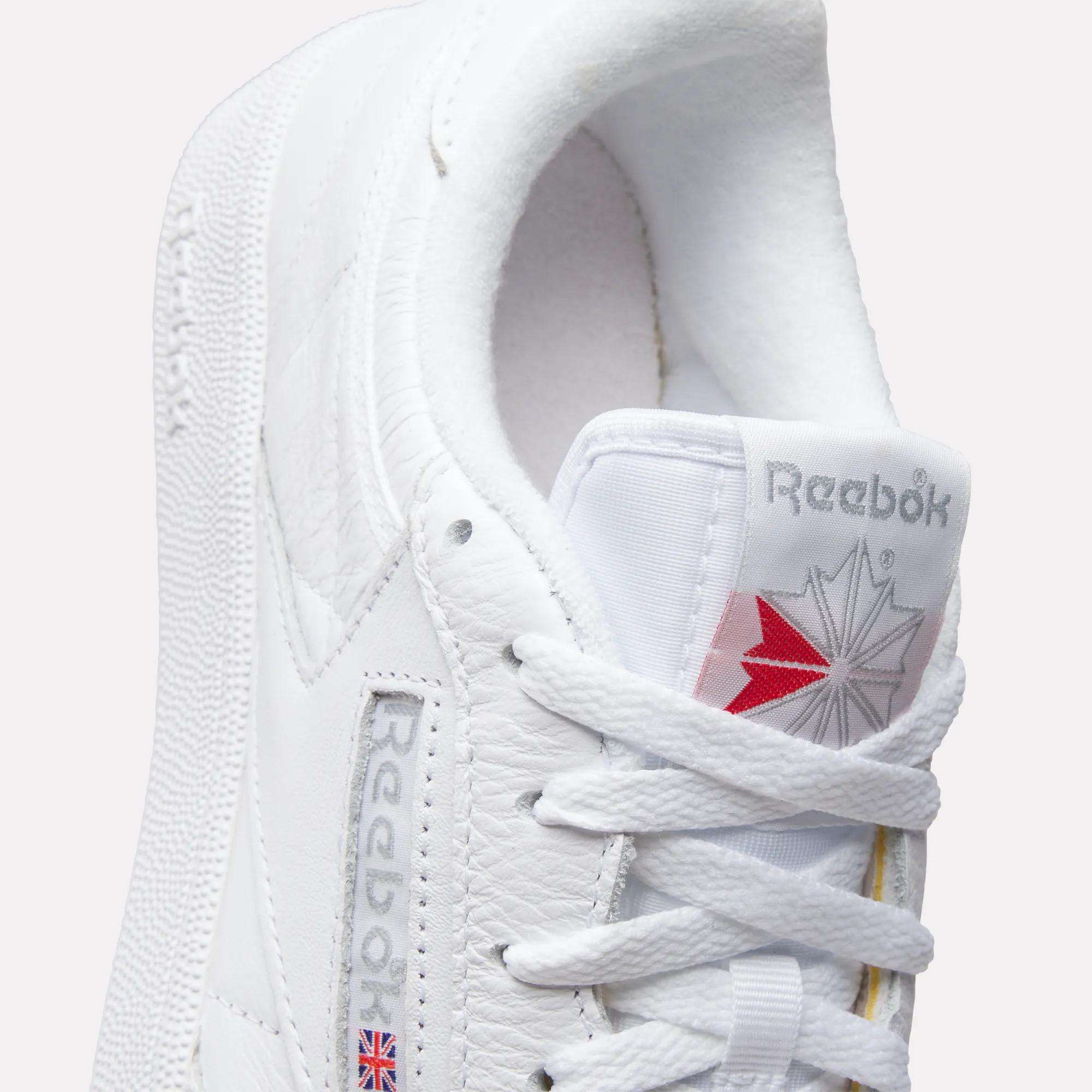 Close-up of Reebok Club C 85 Shoes, featuring white leather with textured details, white laces, the Reebok logo and star on the tongue, plus side branding with a Union Jack flag.