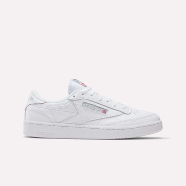 A white Reebok Club C 85 shoe with a classic low-top leather design, featuring the Reebok logo and Union Jack on the side, displayed on a plain light background. This tennis-inspired sneaker blends heritage and style.