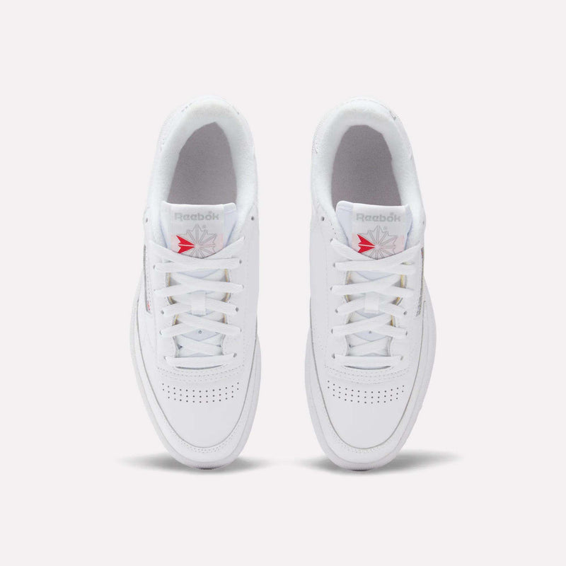 A pair of Reebok Club C 85 Shoes in white leather, seen from above, with white laces, perforated toe boxes, and red and gray Reebok logos on the tongues for a classic tennis-inspired style.