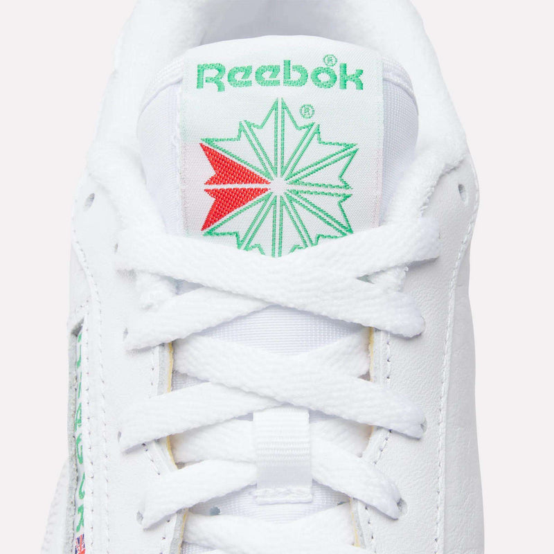 Close-up of Reebok Club C 85 Shoes in white leather, featuring the tongue with green Reebok branding and star graphic, plus crisscrossed white laces—classic tennis-inspired style.