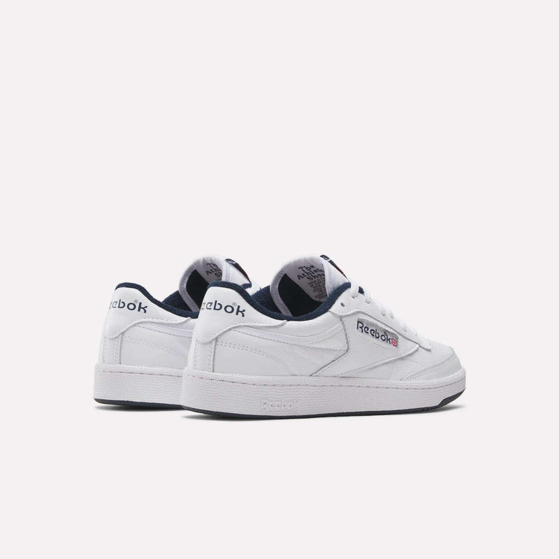 A pair of white Reebok Club C 85 Shoes with navy blue accents and logo, displayed on a plain light background. One shoe is angled forward, revealing the tennis-inspired branding on the side and heel.