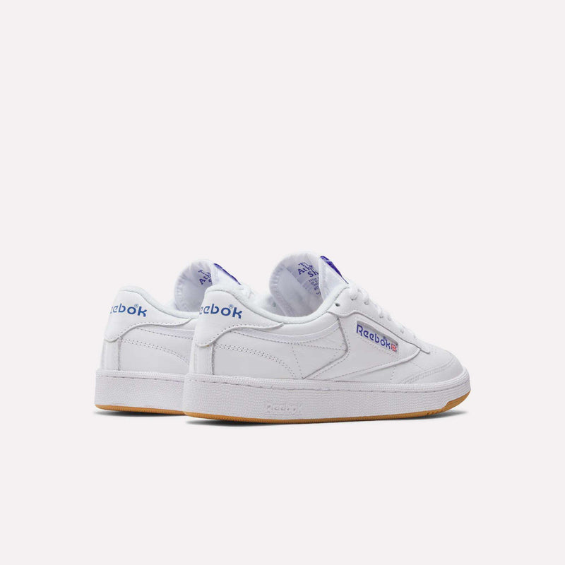 The Reebok Club C 85 Shoes are white leather low-tops featuring purple and red branding, gum soles, and a classic design, shown on a light background.