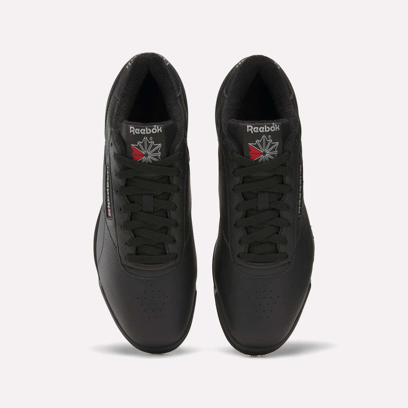 Top view of Reebok Men's Exofit Lo Shoes in black with black laces, the Reebok logo, and a red and white starburst on each tongue. The low-profile shoes are placed side by side on a light background.