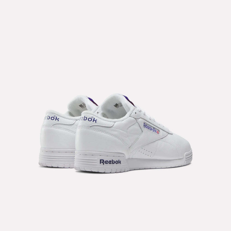 A pair of Reebok Men's Exofit Lo Shoes in white with purple and blue accents, shown from the back and side against a plain light background. The Reebok logo appears on both the heels and sides.