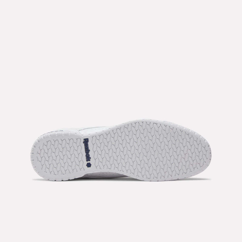 The image features the white sole of the Reebok Men's Exofit Lo Shoes. It displays a herringbone tread pattern and a navy blue Reebok logo near the heel, set against a light pink background.