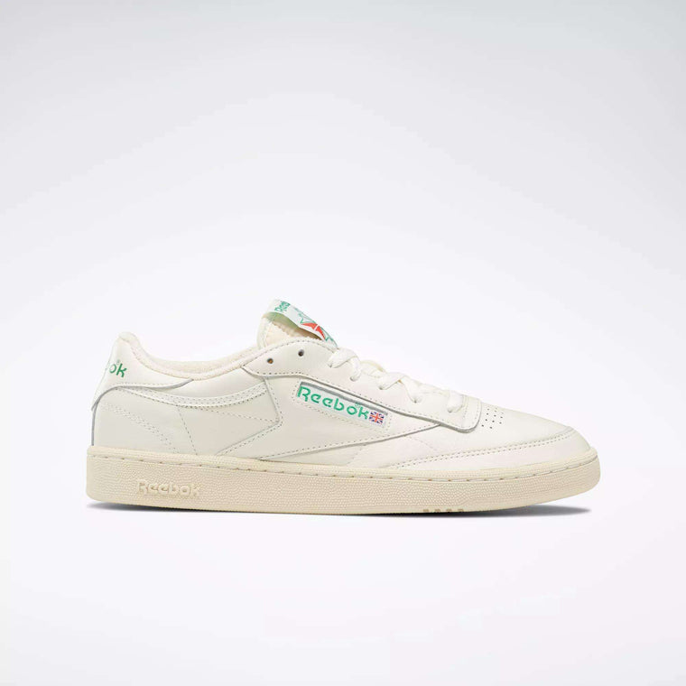 The Reebok Club C 85 Vintage Shoes feature a white leather upper, green and red side logo, green branding on the heel and tongue, and a beige sole, displayed against a plain light background.