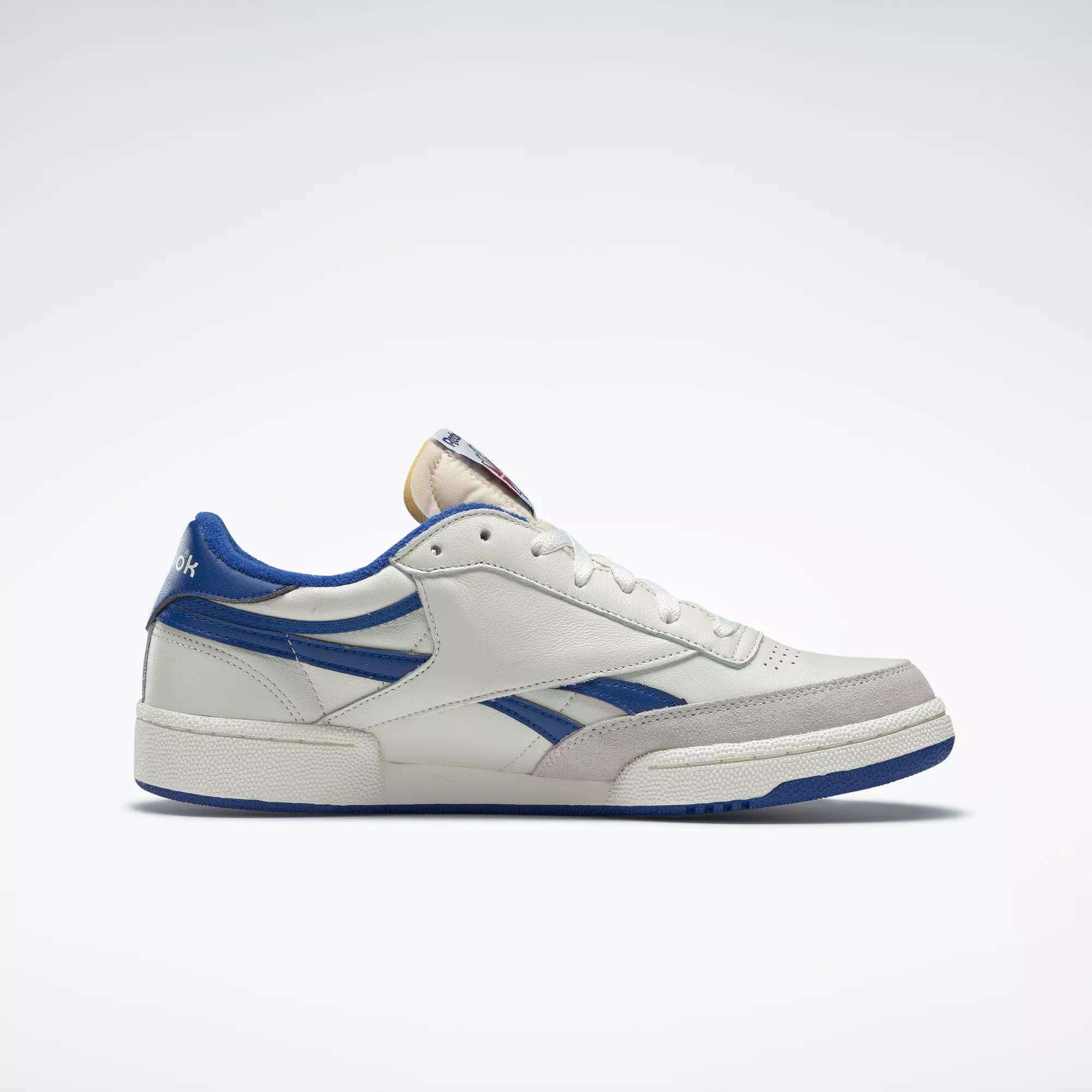 The Reebok Men's Club C Revenge Vintage Shoes feature a white base with blue accents, blue logo, beige tongue, and grey toe cap. Shown in side profile on a light background, these tennis-inspired sneakers add retro style to any outfit.
