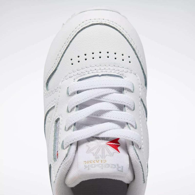 Close-up of Kids' Classic Leather Shoes - Baby & Toddler by Reebok, featuring white leather, laces, perforated toe box, and tongue with silver and red Reebok branding—ideal for active toddlers.
