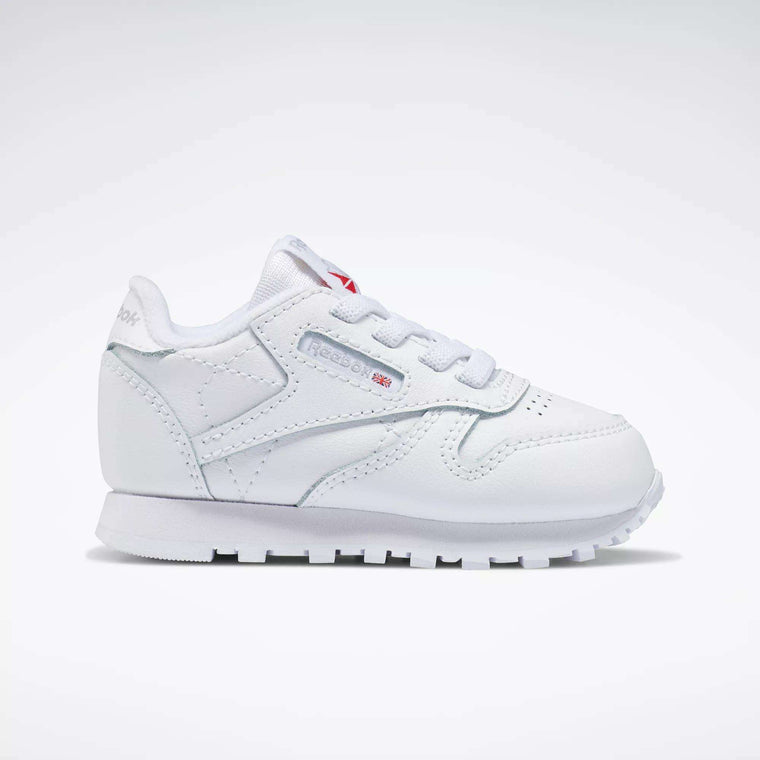 The Reebok Kids' Classic Leather Shoes for babies and toddlers feature crisp white laces, stitching details, and the iconic logo with a small Union Jack on the side, shown against a plain white background.