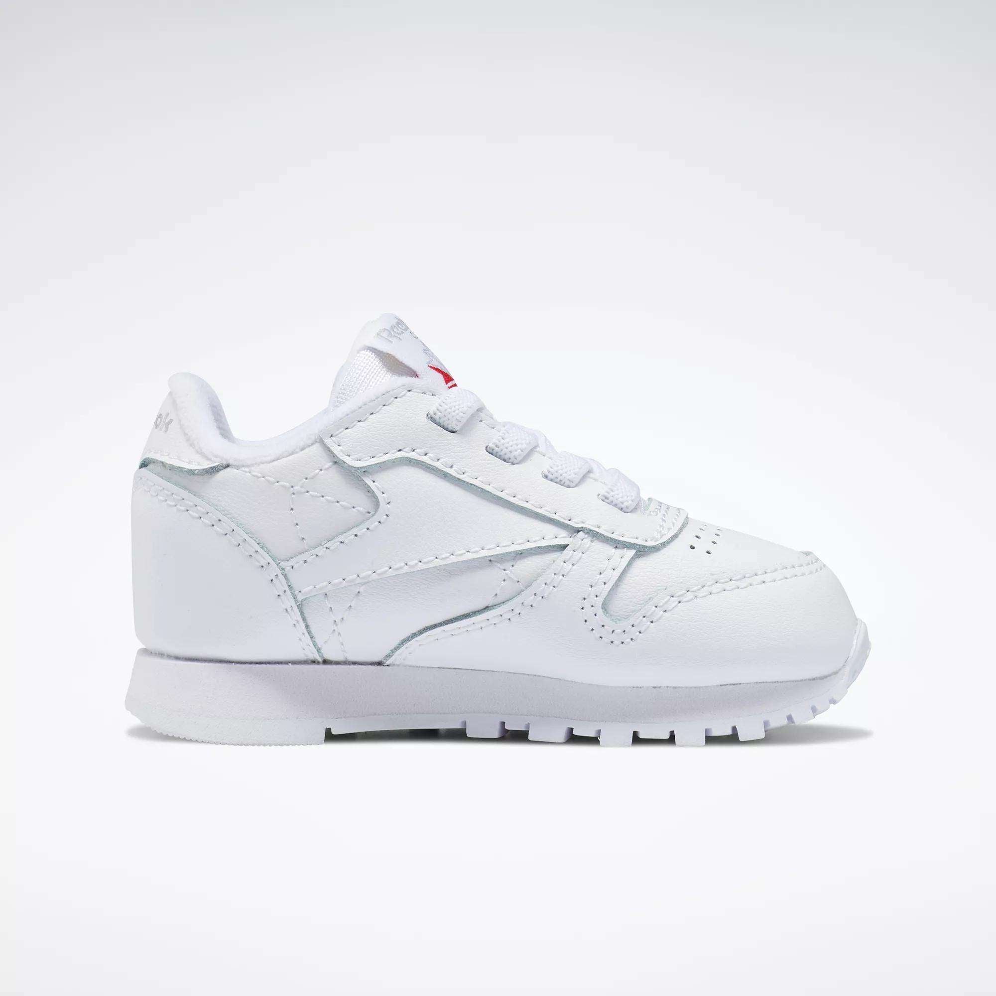 The Reebok Kids' Classic Leather Shoes - Baby & Toddler, shown in profile on a white background, feature white laces, detailed stitching, and a lightly textured sole.