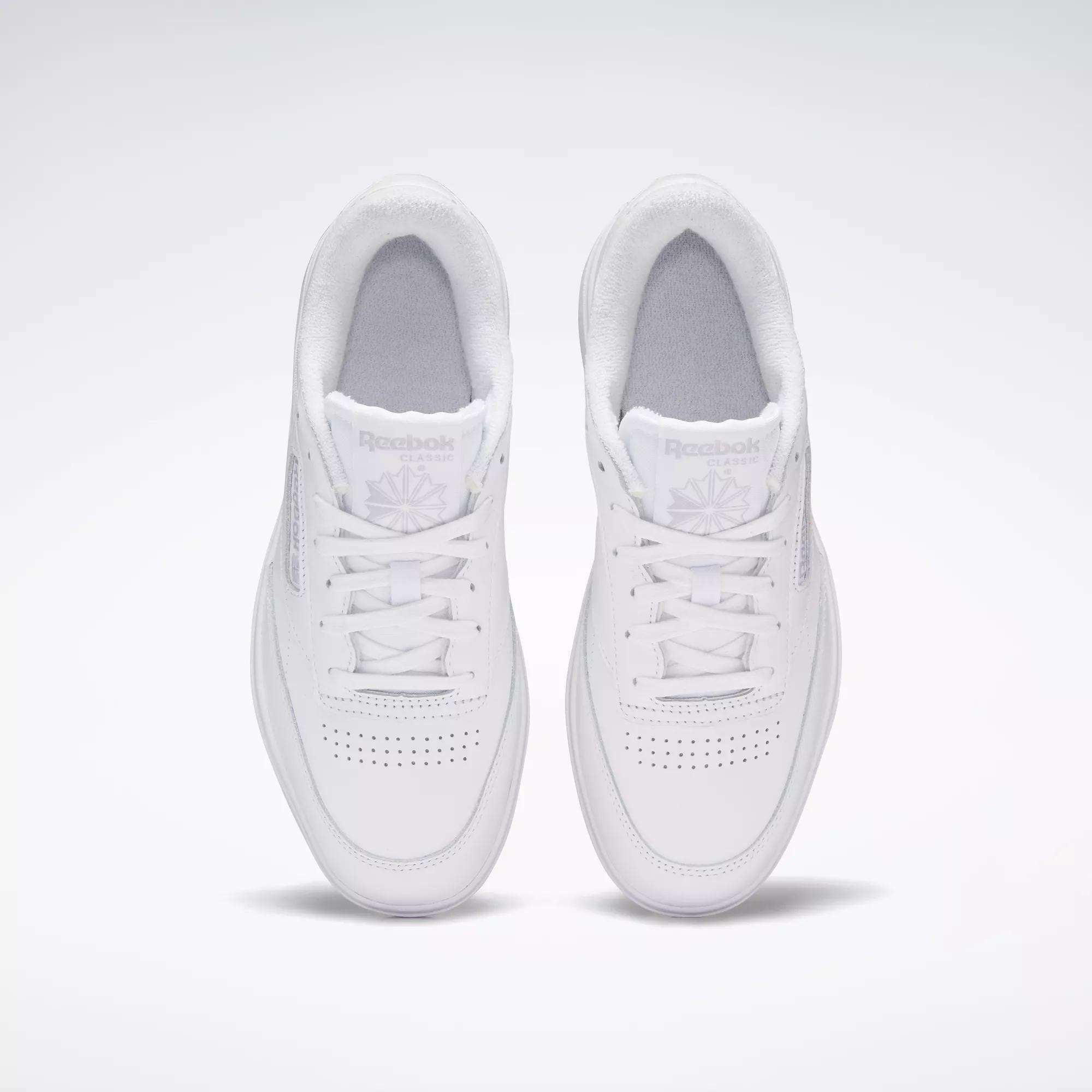 A pair of Reebok Women's Club C Double Shoes in white, seen from above on a light background, highlighting the perforated toe and Reebok logo on each tongue.