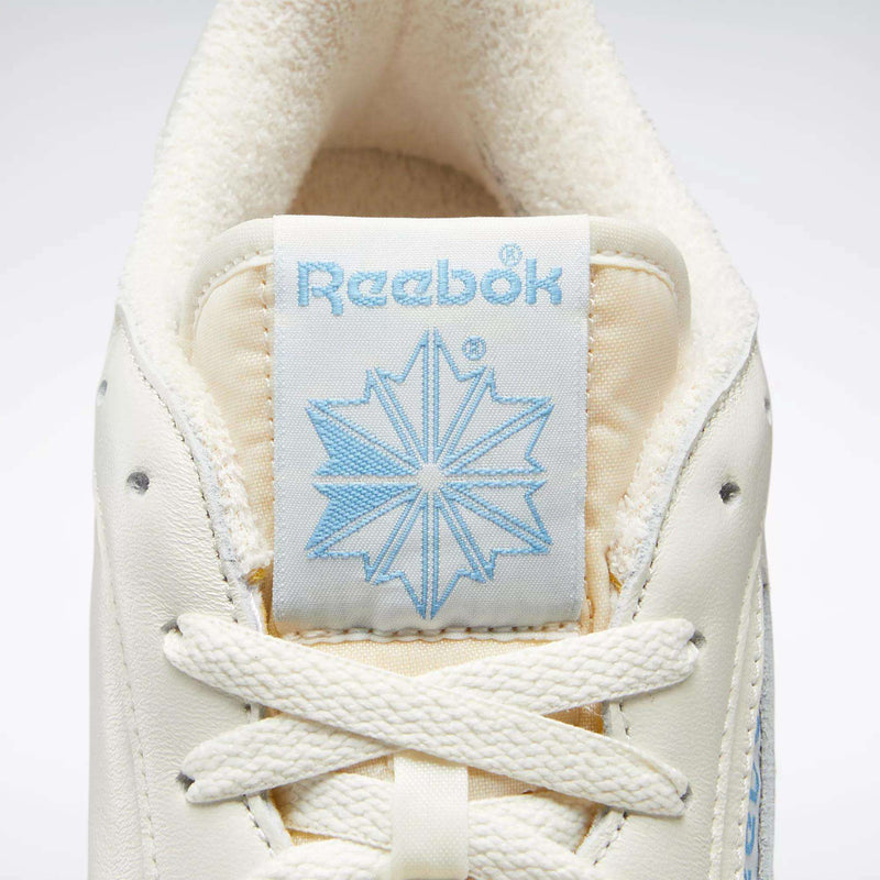 Close-up of a Reebok Club C 85 Vintage Shoes' tongue, featuring a light blue Reebok logo and star, off-white laces, plush inner lining at the top, and premium leather upper for a classic court-inspired look.