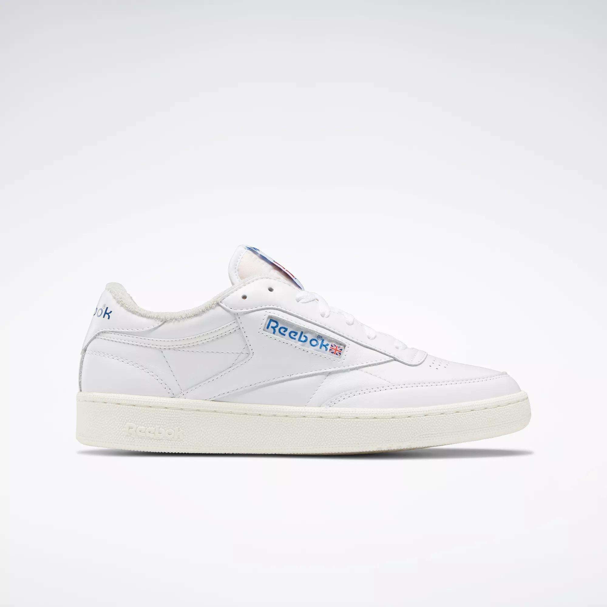 The Reebok Club C 85 Vintage Shoes feature a white leather upper with blue and red branding on the side and tongue, a low-top design, and a textured off-white sole with lightweight cushioning. Displayed on a plain white background.