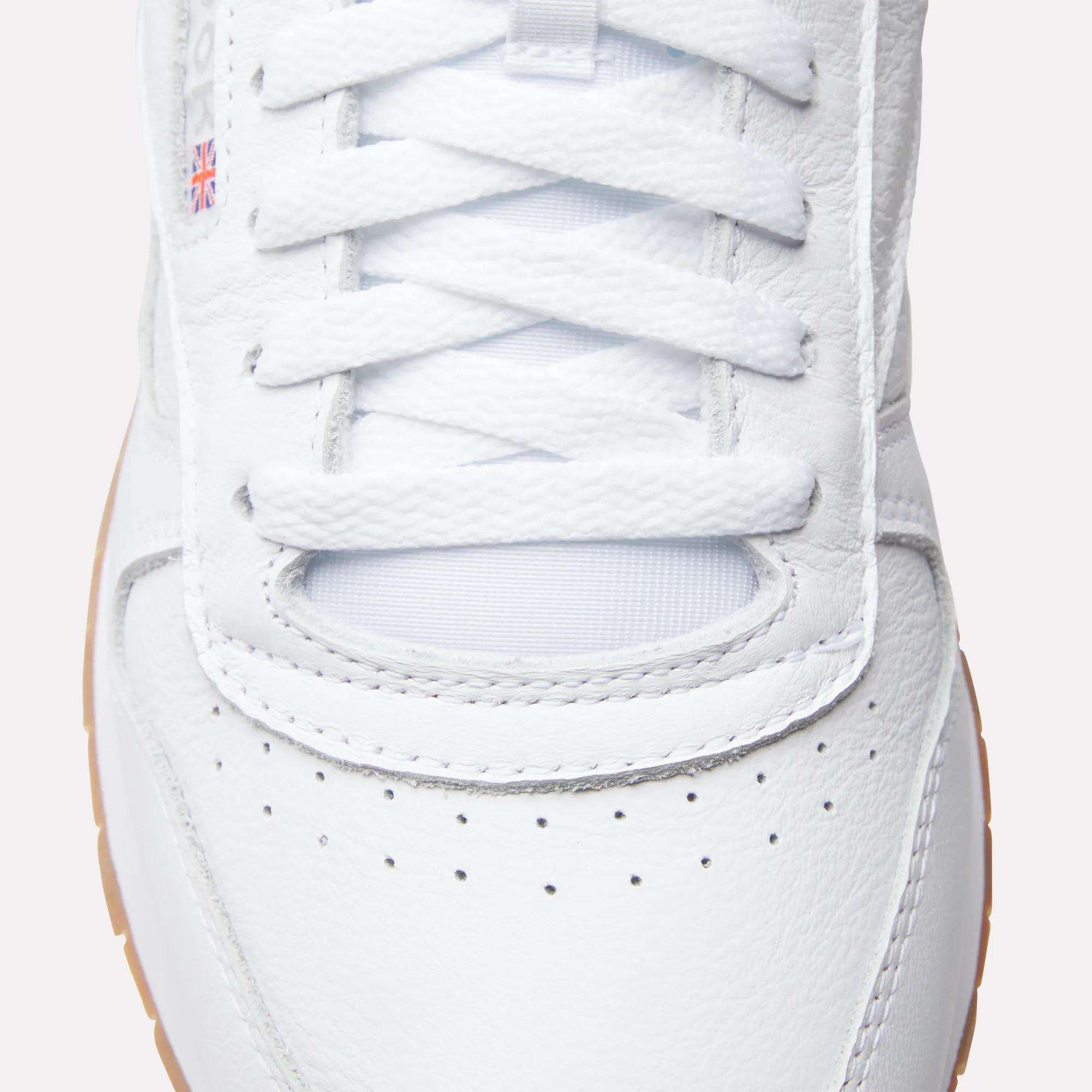 Top view close-up of Reebok Classic Leather Shoes featuring white laces, a durable leather upper, perforated toe area, small British flag detail on the side, and a light brown outsole.