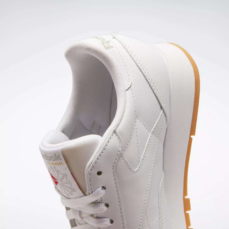 A close-up of Reebok Classic Leather Shoes showcases their retro style, durable white leather upper, gum sole, and visible Reebok branding on the side against a plain light background.