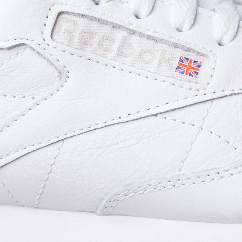 Close-up of the Reebok Classic Leather Shoes in white, highlighting the embossed Reebok logo, a small Union Jack flag on the side, and visible stitching for a timeless retro-inspired look.