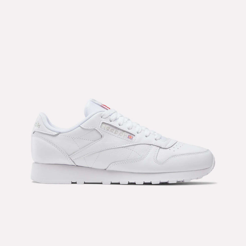The Reebok Classic Leather Shoes feature a classic white low-cut design with lace-up front and subtle Reebok branding on the side, tongue, and heel, shown against a plain light background for a timeless retro look.