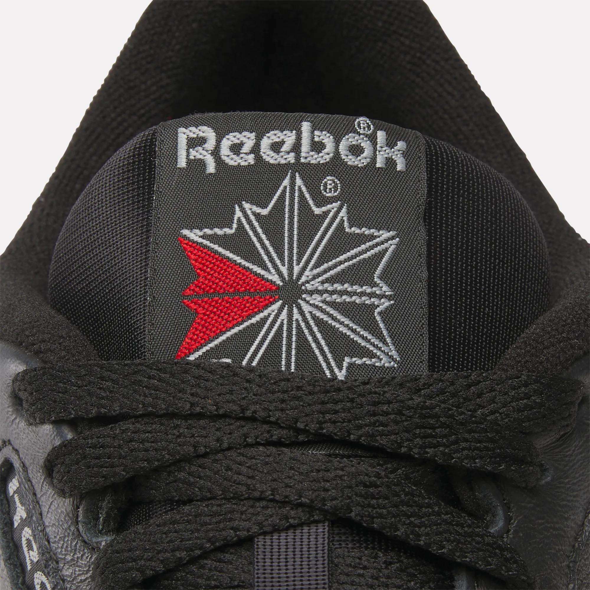 Close-up of the tongue on Reebok Classic Leather Shoes, featuring the embroidered Reebok logo with red and white detail and black laces, emphasizing the retro style of this iconic footwear.