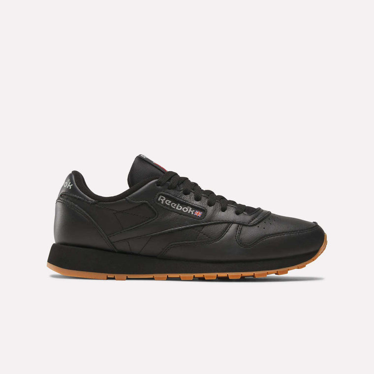 The Reebok Classic Leather Shoes feature a black leather upper, gum sole, black laces, and side Reebok logo. Shown on a white background, their durable construction and retro style make them a timeless choice.