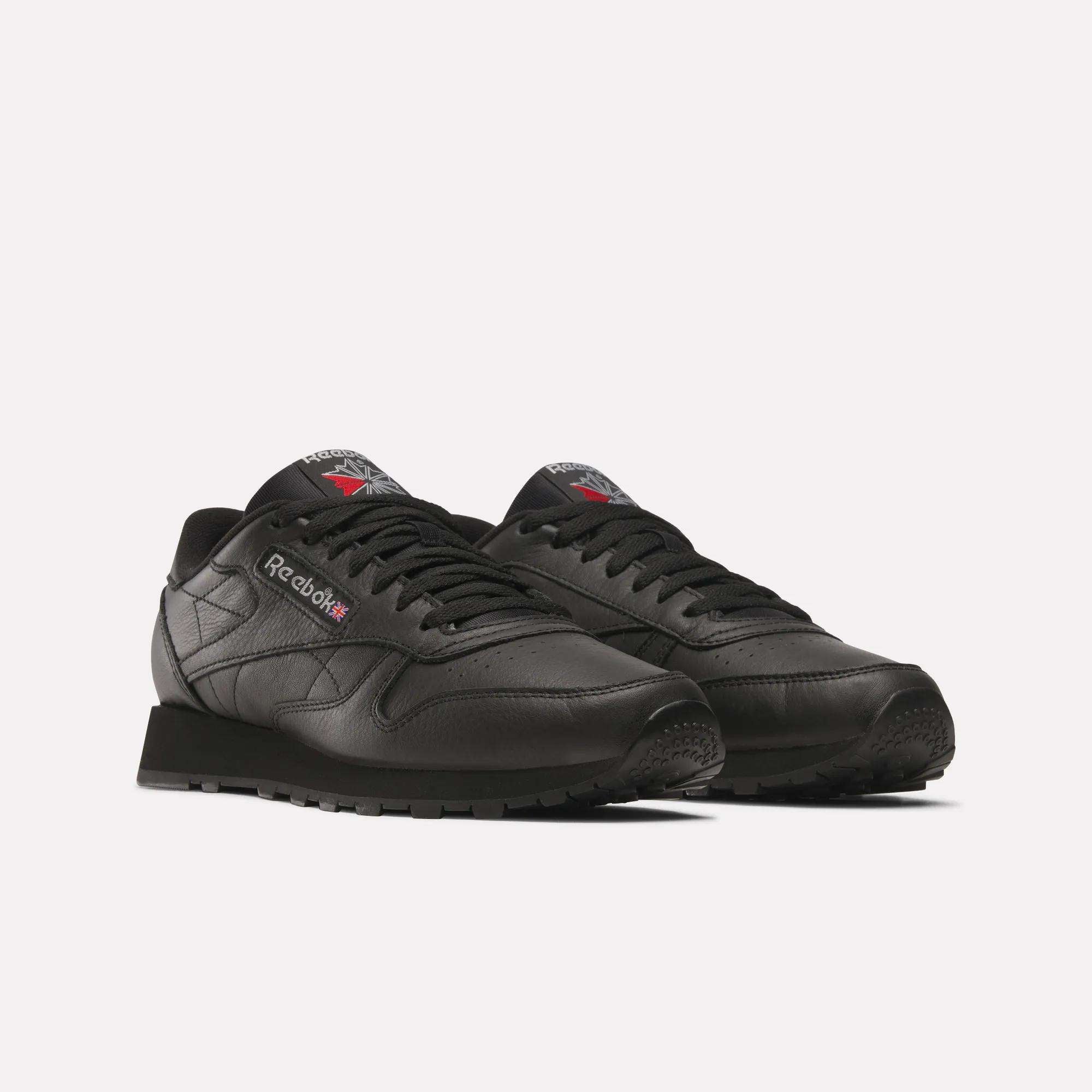 A pair of Reebok Classic Leather Shoes in black, featuring black laces and soles, a durable leather upper, and the Reebok logo on the sides and tongues, displayed against a plain white background.