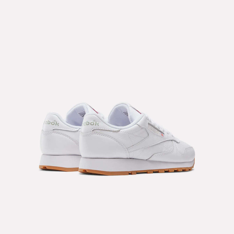 Two white Reebok Women's Classic Leather Shoes with gum soles are shown on a white background, highlighting the back and side views and featuring cushioned midsoles for comfort.