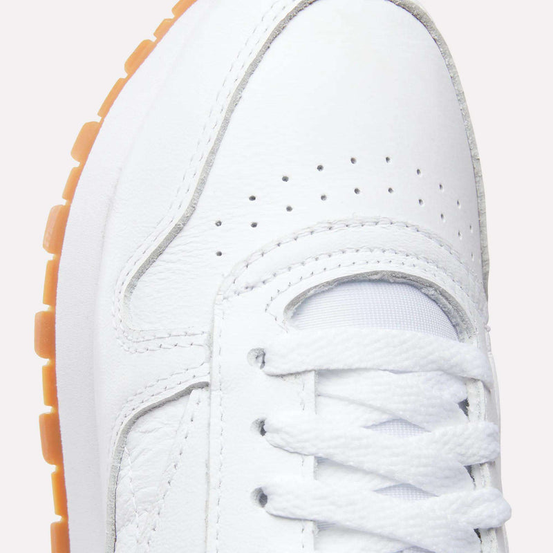 Close-up of the toe and laces on the Reebok Women's Classic Leather Shoes, showing the white leather, gum sole, perforated details, stitched panels, and cushioned midsole for comfort.
