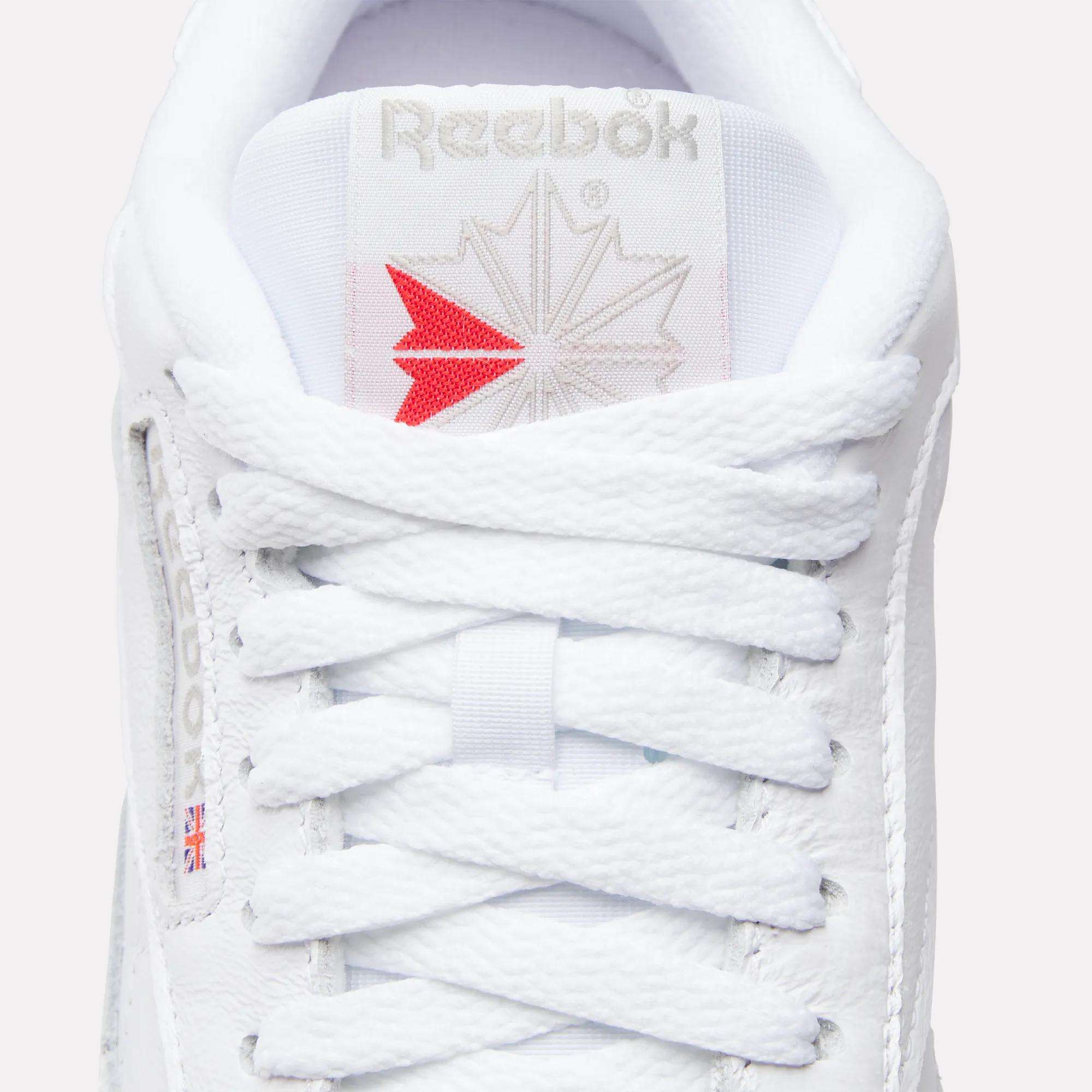 Close-up of the tongue and laces on Reebok Women's Classic Leather Shoes, featuring the brand logo and a small Union Jack flag. The cushioned midsole adds comfort, and the crisscross lacing is neatly tied.