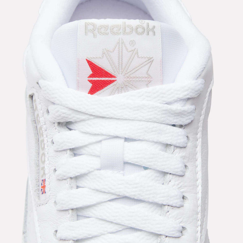 Close-up of the tongue and laces on Reebok Women's Classic Leather Shoes, featuring the brand logo and a small Union Jack flag. The cushioned midsole adds comfort, and the crisscross lacing is neatly tied.