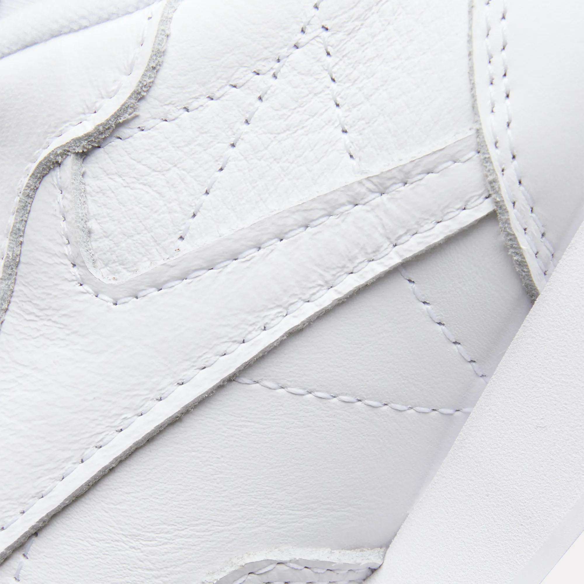 Close-up of Reebok Women's Classic Leather Shoes, highlighting detailed stitching, layered panels, textured leather upper, and a cushioned midsole for comfort.