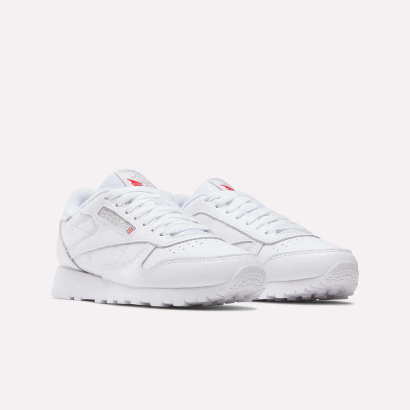 A pair of Women's Classic Leather Shoes by Reebok, featuring cushioned midsoles, white laces and soles, with subtle grey and red logo accents, displayed on a light background.