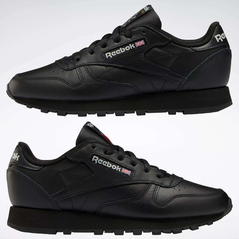 Two black Reebok Women's Classic Leather Shoes are shown in side view, one above the other, on a white background. The cushioned midsole, Reebok logo, and Union Jack flag appear on the sides and heel.